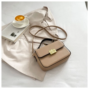 Detailed view of the gold square rotating lock and brown leather texture on handbag