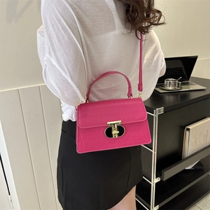 Magenta crocodile pattern handbag with golden T-lock shown on model in minimalist interior