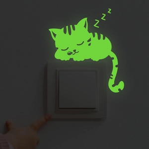 Luminous sleeping cat wall sticker glowing in the dark above a light switch