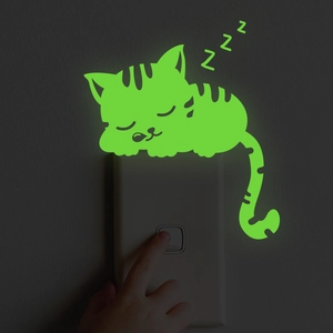 Luminous green cat wall sticker glowing in dark near light switch in bedroom decor