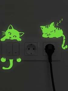 Luminous cat switch stickers showing soft green glow on a white socket in the dark