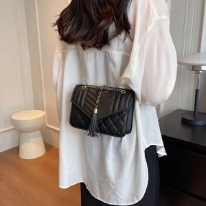 Elegant black quilted crossbody bag with gold chain strap and tassel charm detail