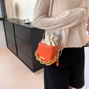 Chic orange bucket bag with checkered texture, chunky gold chain and drawstring inner pouch
