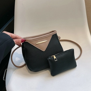 Detail of trendy black litchi grain bucket bag set with contrast tan trim and gold hardware