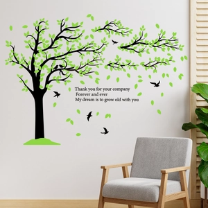 Green tree wall sticker with birds and quote above a grey sofa in a modern living room