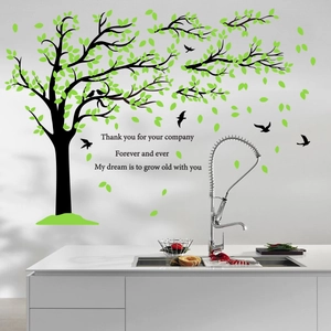Wall sticker with green tree leaves, black birds, and romantic quotes on white wall