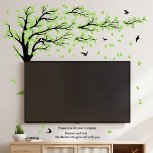 Creative black tree wall sticker with green leaves, birds, and romantic quote in living room