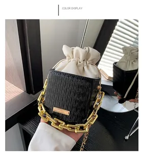 Black bucket bag with textured pleats, white drawstring liner, and chunky gold chain handle
