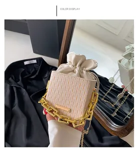 Beige pleated square bucket bag with chunky gold chain strap and drawstring closure
