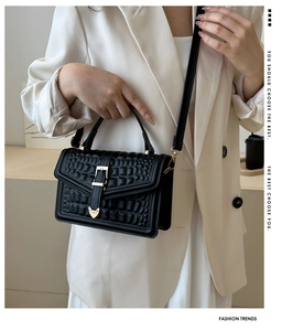 Detail of black crocodile texture handbag with gold hardware and heart accent