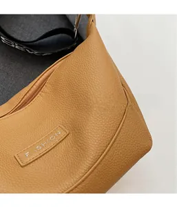 Détail du sac en cuir grainé avec étiquette fashion et bandoulière tissée