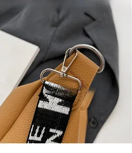 Détail de sac en cuir grainé avec fermoir argenté et bandoulière en jacquard