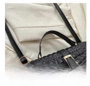 Close-up of black crocodile pattern handbag with gold metal buckle and lobster clasp detail