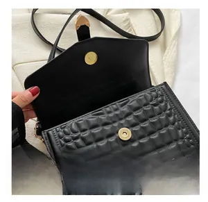 Close-up of black crocodile pattern leather handbag with gold magnetic snap buttons