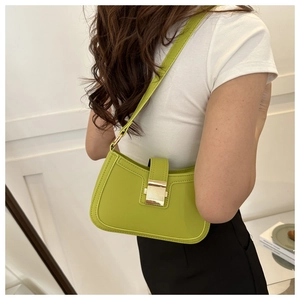 Détail du sac selle en cuir vert avec boucle dorée porté par un mannequin chic