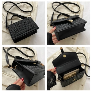 Detail of black faux leather handbag with square texture and gold heart-shaped buckle