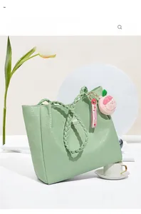 Détail du sac cabas vert menthe en cuir gaufré avec breloque pêche en peluche