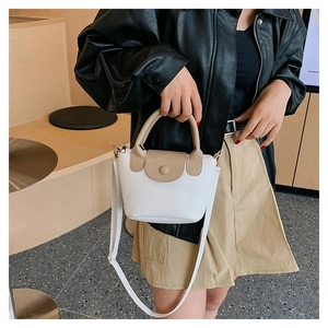 Detail of a mini two-tone bucket bag featuring lychee texture and a detachable strap