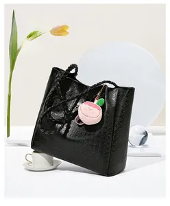 Détail du sac cabas noir à motif pied-de-poule avec pendentif pêche en peluche rose