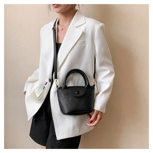 Detailed side view of black lychee grain leather bucket bag with top handles and strap