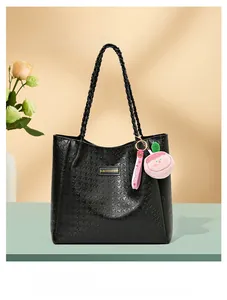 Détail du cabas noir motif pied-de-poule avec logo doré et pendentif pêche en peluche