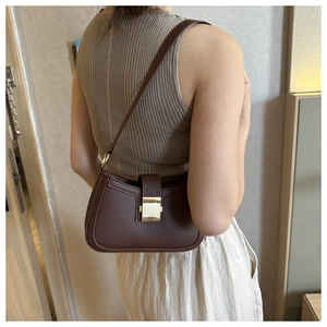 Détail d'un sac bandoulière marron avec boucle en métal doré sur un mannequin femme