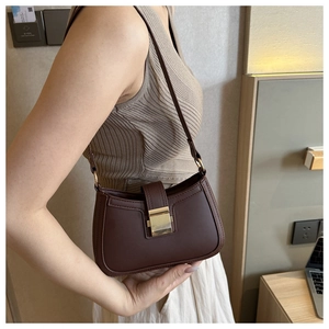 Vue détaillée d'un sac besace en cuir marron avec boucle dorée porté à l'épaule