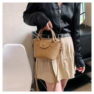 Detail of khaki bucket bag showing the lychee texture, round flap, and top handle