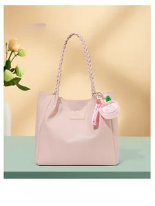 Détail du sac cabas rose gaufré avec poignées tressées et charm de fruit en peluche