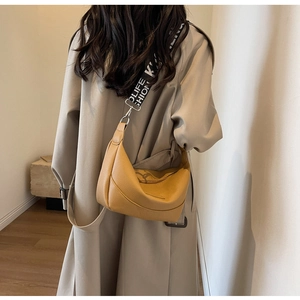 Détail du sac hobo jaune moutarde avec une large bandoulière en tissu imprimé lettré