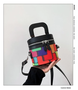 Detail view of colorful cylinder bucket bag with leather handles and silver hardware