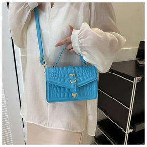 Detail of sky blue crocodile-textured crossbody bag with heart-shaped gold hardware