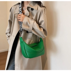Détail du sac demi-lune vert en cuir grainé avec une bandoulière contrastée large