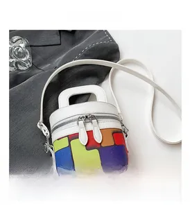 Detail of cylinder bag showing dual metal zippers and colorful geometric pattern
