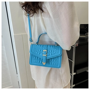 Detail of light blue faux leather crossbody bag with stone texture and heart buckle