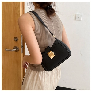 Détail d'un sac sous le bras en cuir noir chic doté d'une boucle carrée dorée vintage