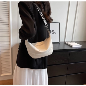 Détail d'un sac hobo en cuir grainé blanc avec une large bandoulière noire à logo imprimé