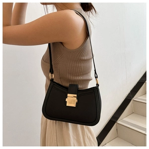 Détail d'un sac sous le bras en cuir noir avec boucle dorée et fine bandoulière