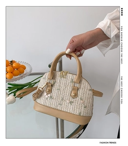 Detail of shell-shaped straw bag with floral lace embroidery and leather handles