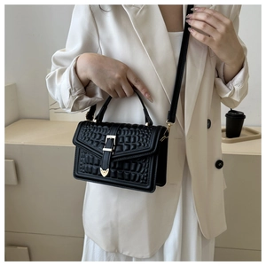 Detail of black crocodile texture bag with gold heart buckle and adjustable strap