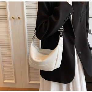 Détail du sac demi-lune blanc avec texture litchi et bandoulière en toile rayée