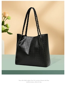 Détail du sac cabas noir avec texture pied-de-poule et anses tressées sur un présentoir