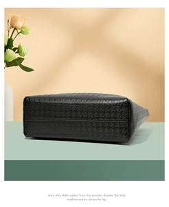 Gros plan sur la texture pied-de-poule gaufrée et le fond solide de ce sac cabas noir