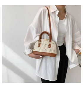 Detail of straw shell bag with delicate floral embroidery and brown leather trim