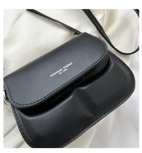 Close-up of black crossbody bag featuring two 3D front pockets and silver logo print