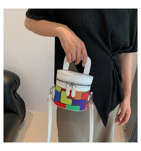 Close-up of a cylindrical bucket bag with colorful geometric patterns and white leather details