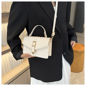 Close-up of cream white crocodile embossed bag with gold heart clasp and shoulder strap