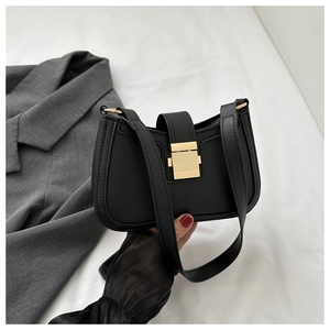 Détail d'un sac à bandoulière noir mat avec une boucle en métal doré rectangulaire chic