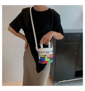 Detail of colorful geometric pattern cylinder bucket bag held by a model in casual outfit