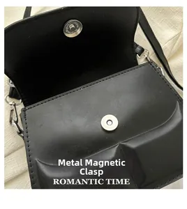 Close-up of silver magnetic metal clasp on black leather shoulder bag detail